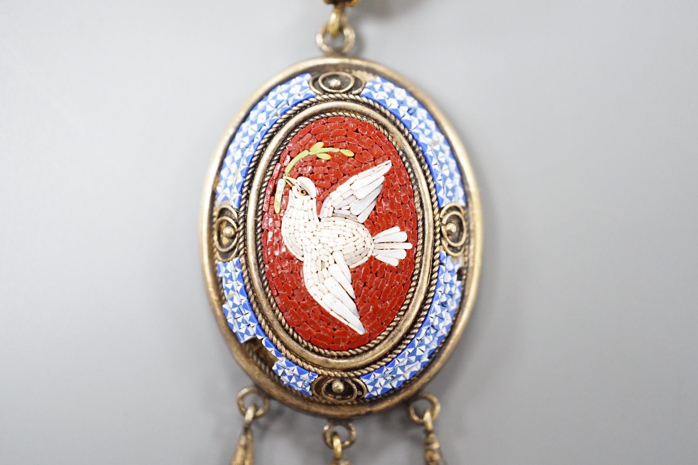 A Victorian yellow metal and micro mosaic set drop mourning pendant, depicting a dove with olive branch, with glazed back, overall 7cm, gross weight 10 grams (a.f.).